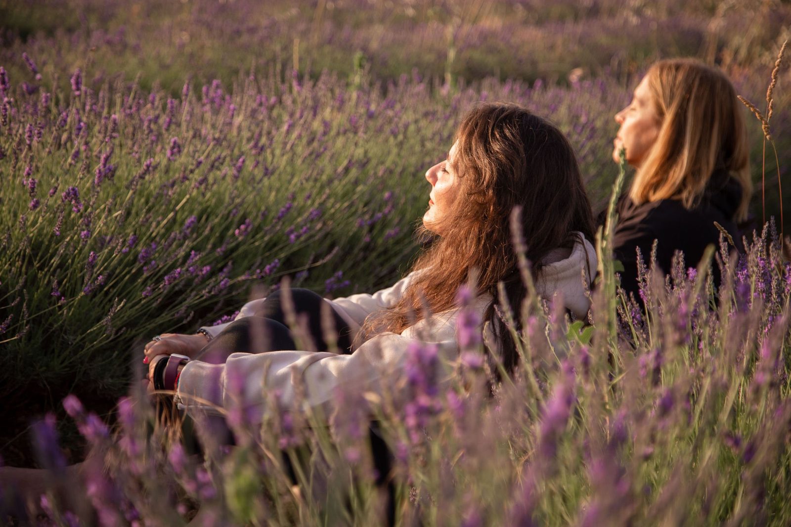 Dos mujeres relajándose en un campo de lavanda al atardecer